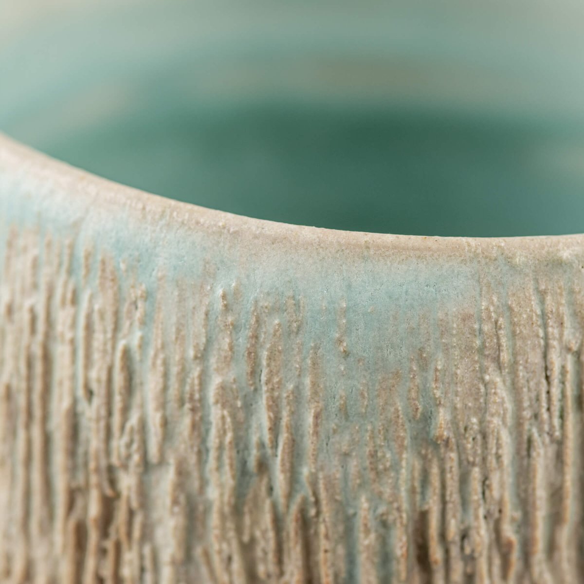 Close-up of pottery mug rim with aqua glaze and rustic carved texture, handmade ceramic tableware for fine dining and hotels.