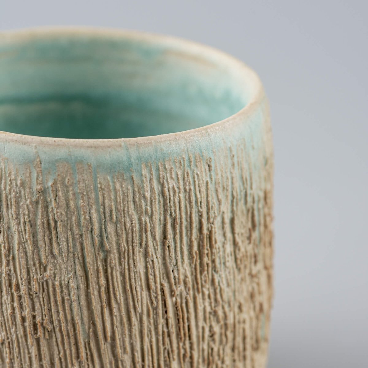 Detail of textured ceramic surface with turquoise accents, collectible pottery for fine dining.