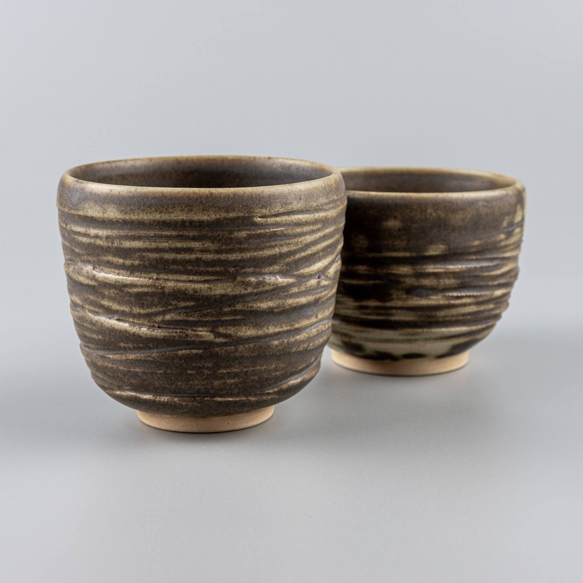 Artisanal ceramic mugs in earthy tones with natural texture, perfect for interior design, collectible pottery, and gift ideas