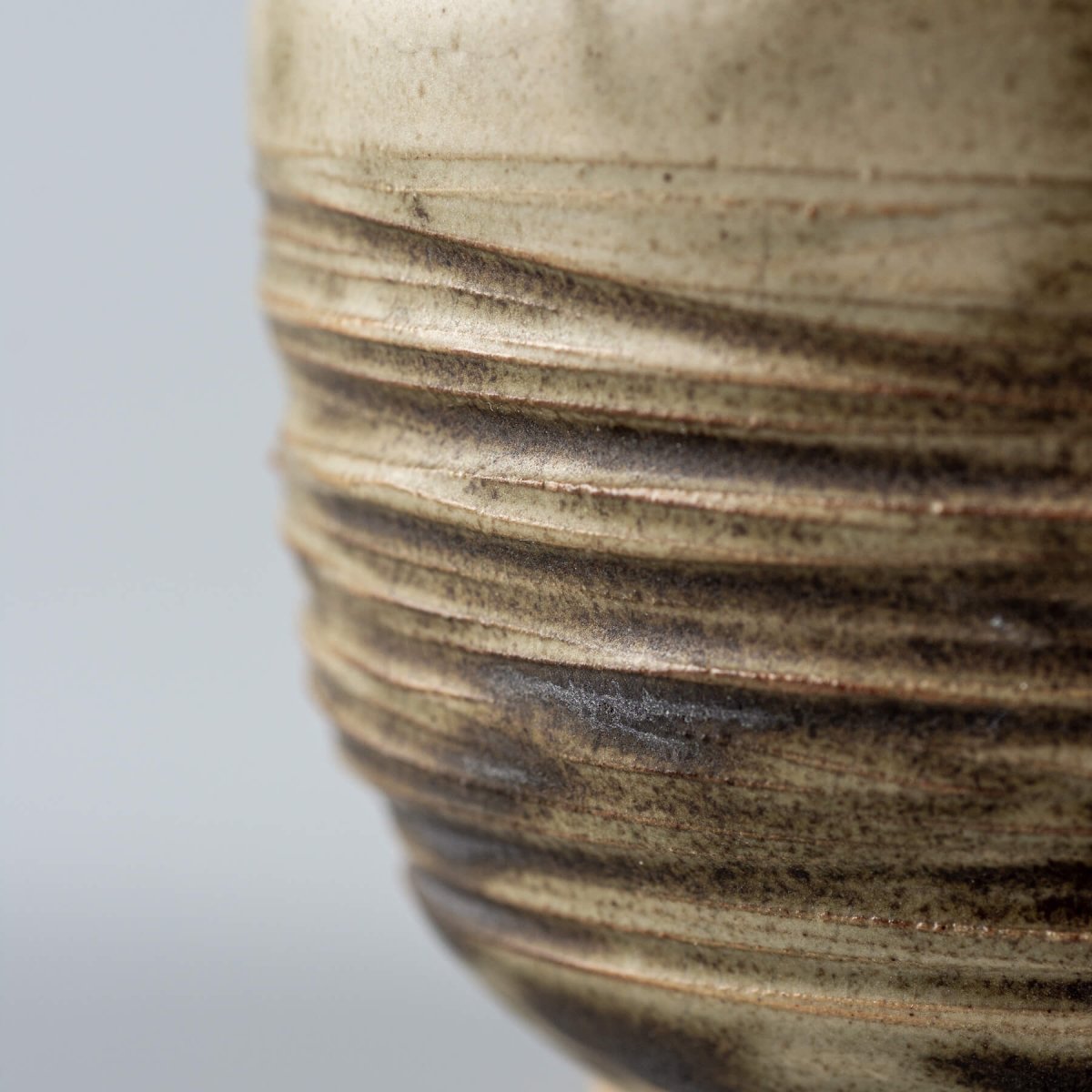Close-up of carved ceramic texture with earthy olive tones, artisanal tableware for home and boutique hotels.