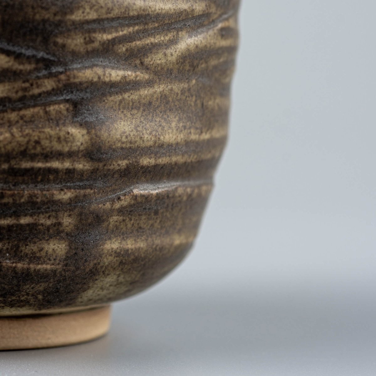 Side view of artisanal ceramic mug with engraved lines and olive-green glaze, collectible handmade decor.