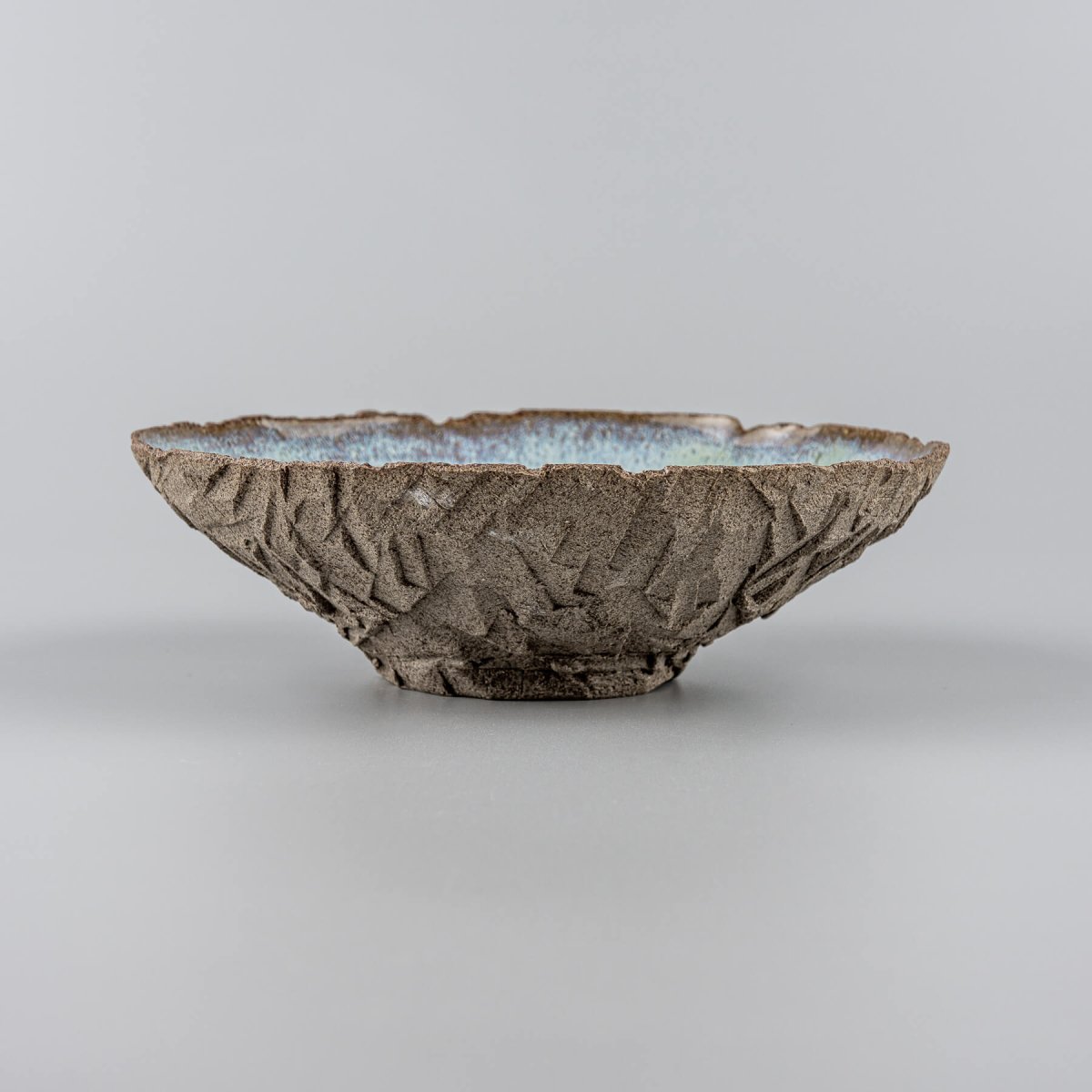 Side view of handmade bowl with rough exterior and curved form.