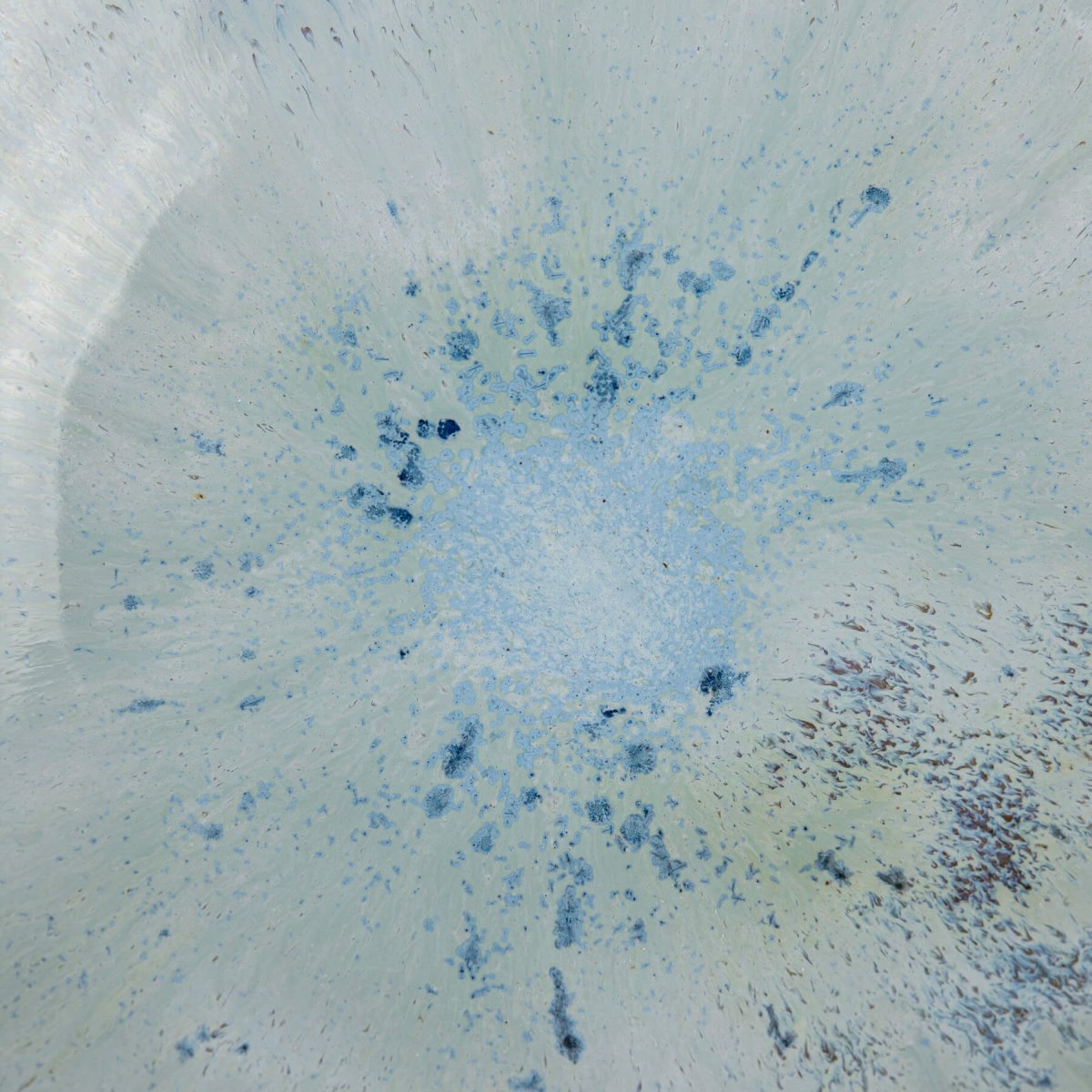 Detail of glossy blue glaze blending in ceramic bowl interior.
