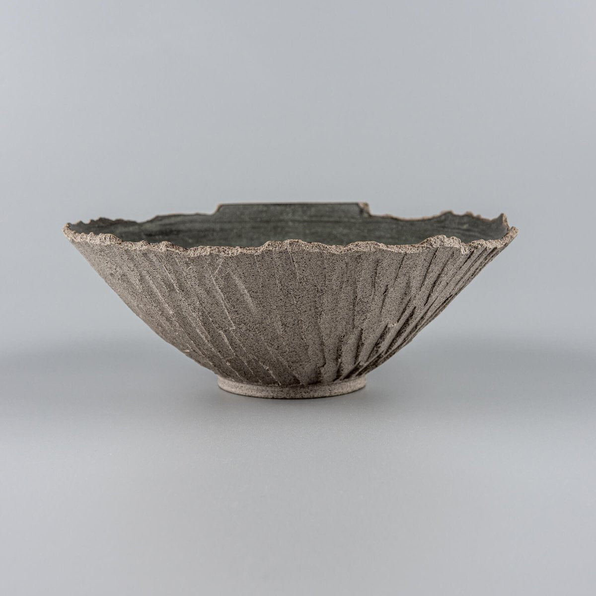 Handmade pottery bowl with textured carved exterior and matte glazed interior, ideal for modern home decor.