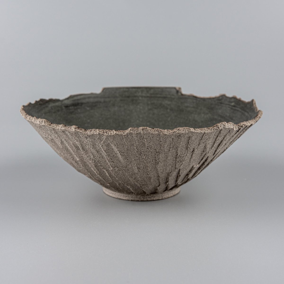 Profile of artisanal bowl with rough exterior and flared form, suited for boutique hotel interiors.