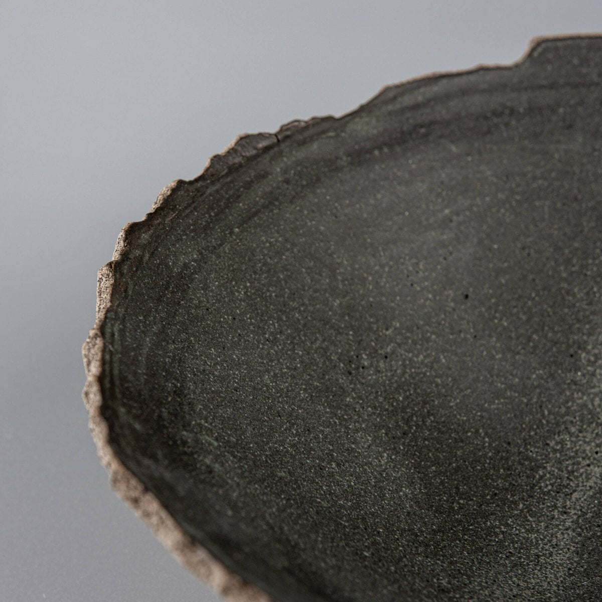 Close-up of uneven hand-shaped rim and natural clay texture on handcrafted bowl for home use.