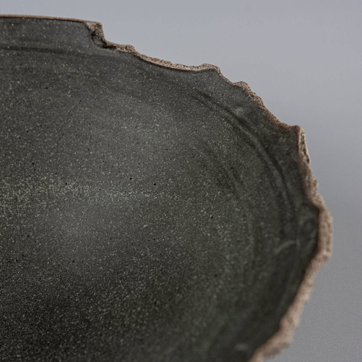 Close-up of uneven hand-shaped rim and natural clay texture on handcrafted bowl for home use.