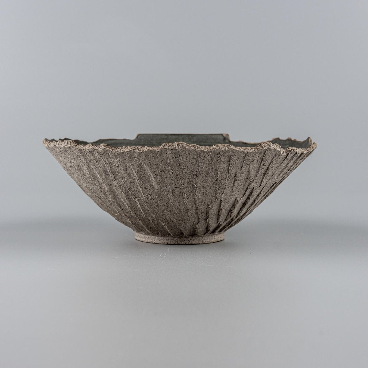 Side angle showing rustic texture of hand-carved ceramic bowl, crafted for fine dining presentation.