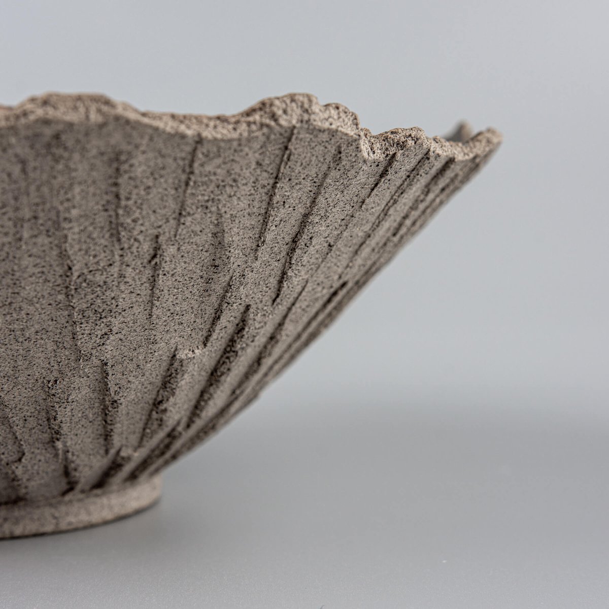 Artisan ceramic bowl highlighting radial carving details and unglazed natural finish, perfect for collectors.