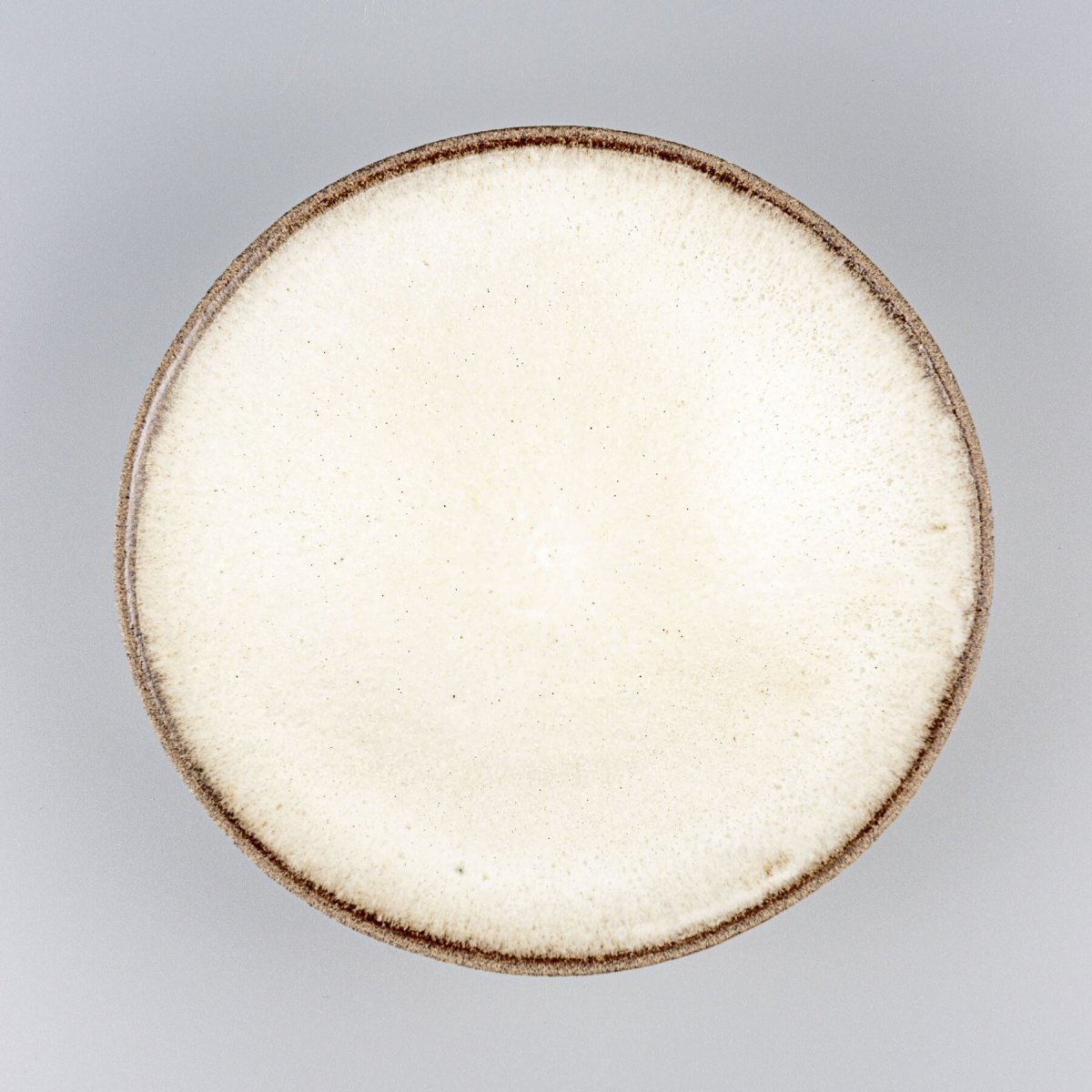 Handmade artisanal ceramic plate with white matte glaze interior for fine dining presentation.