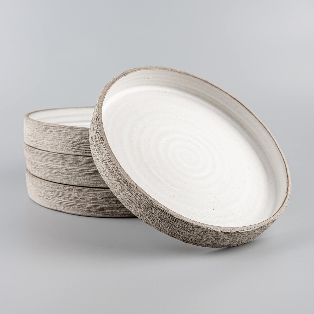 Handmade ceramic dinner plates with tall straight edges and matte white glaze interior.