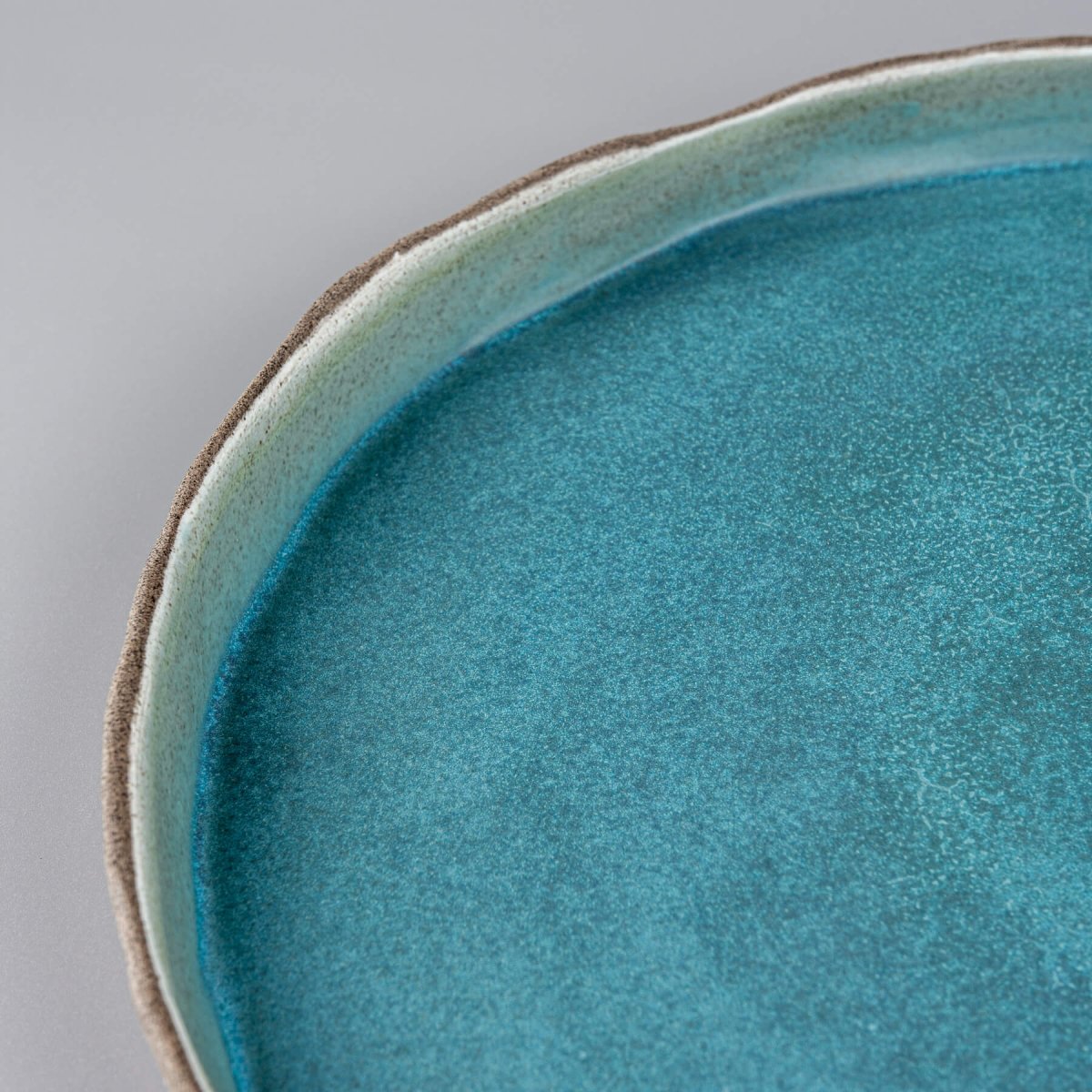 Matte turquoise handmade dinner plate showcasing smooth interior glaze and natural clay contrast.
