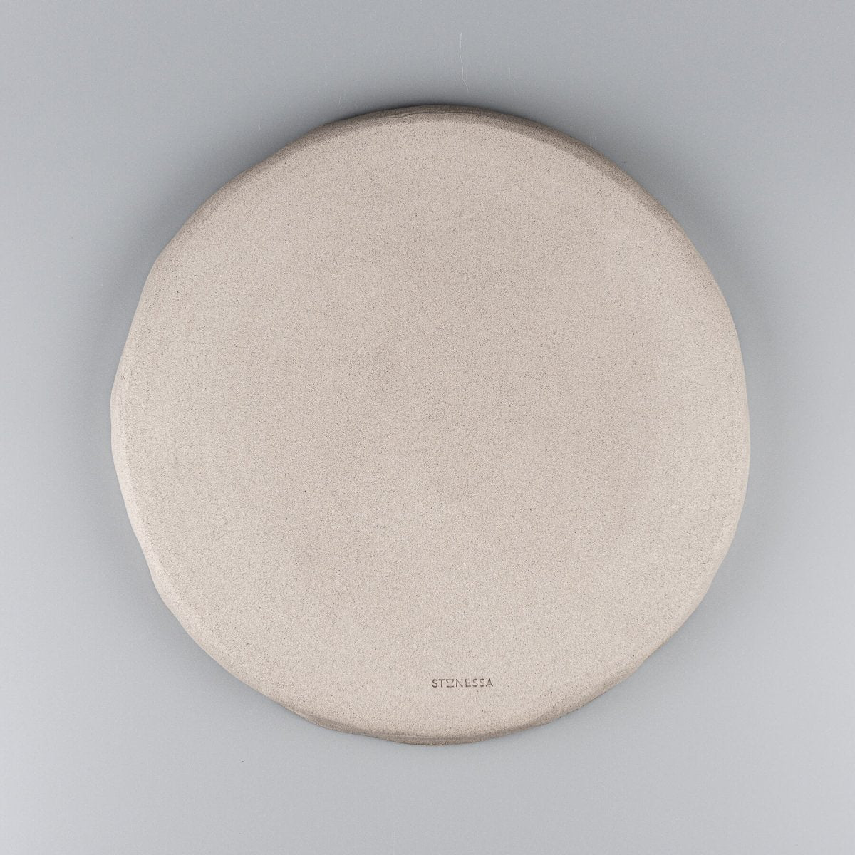Bottom view of handmade dinner plate showing unglazed natural stoneware texture.