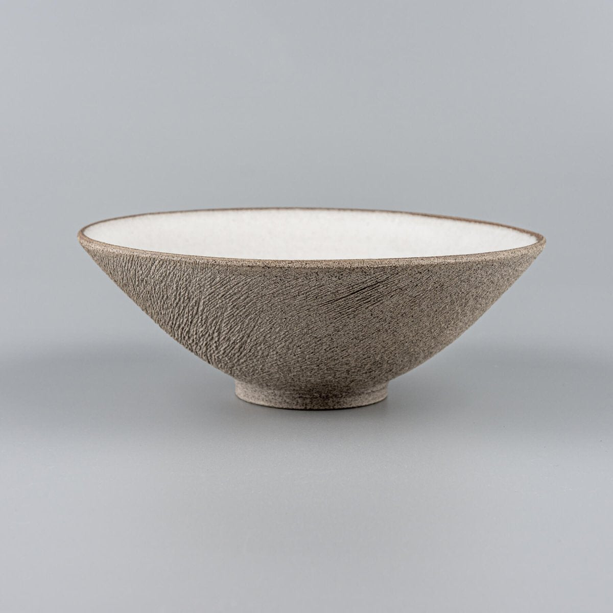 Side profile of conical stoneware bowl with textured surface and elegant form.