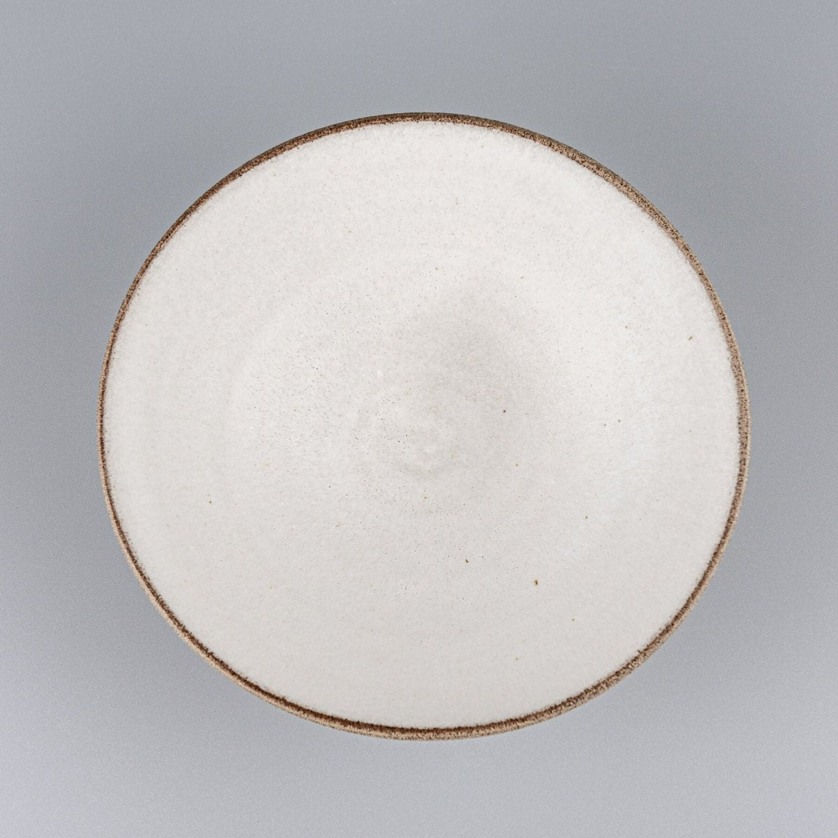 Top view of handmade ceramic bowl with minimal white interior and sharp angled rim.