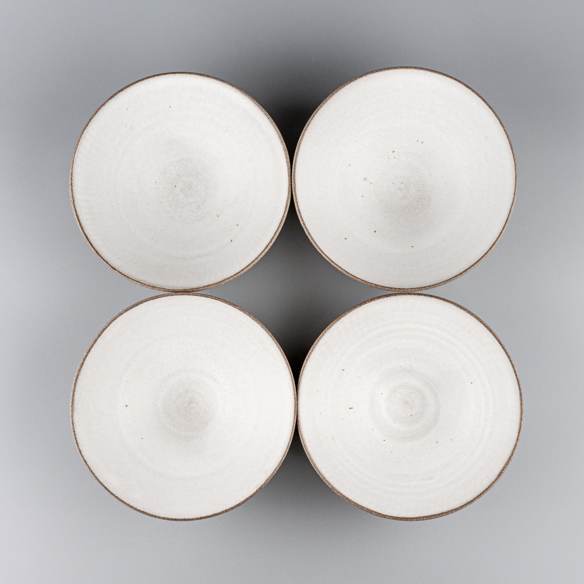 Top view of handmade ceramic bowl set highlighting uniform white matte glaze.
