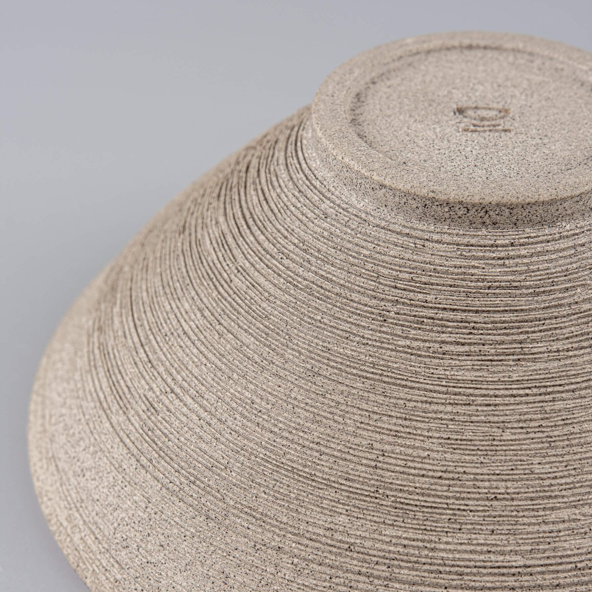 Close-up of rough carved stoneware texture on artisanal ceramic bowl.
