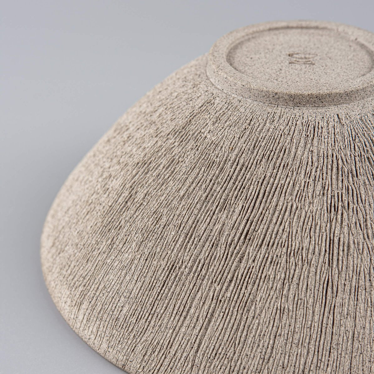 Detail of hand-carved lines on unglazed exterior of pottery bowl.