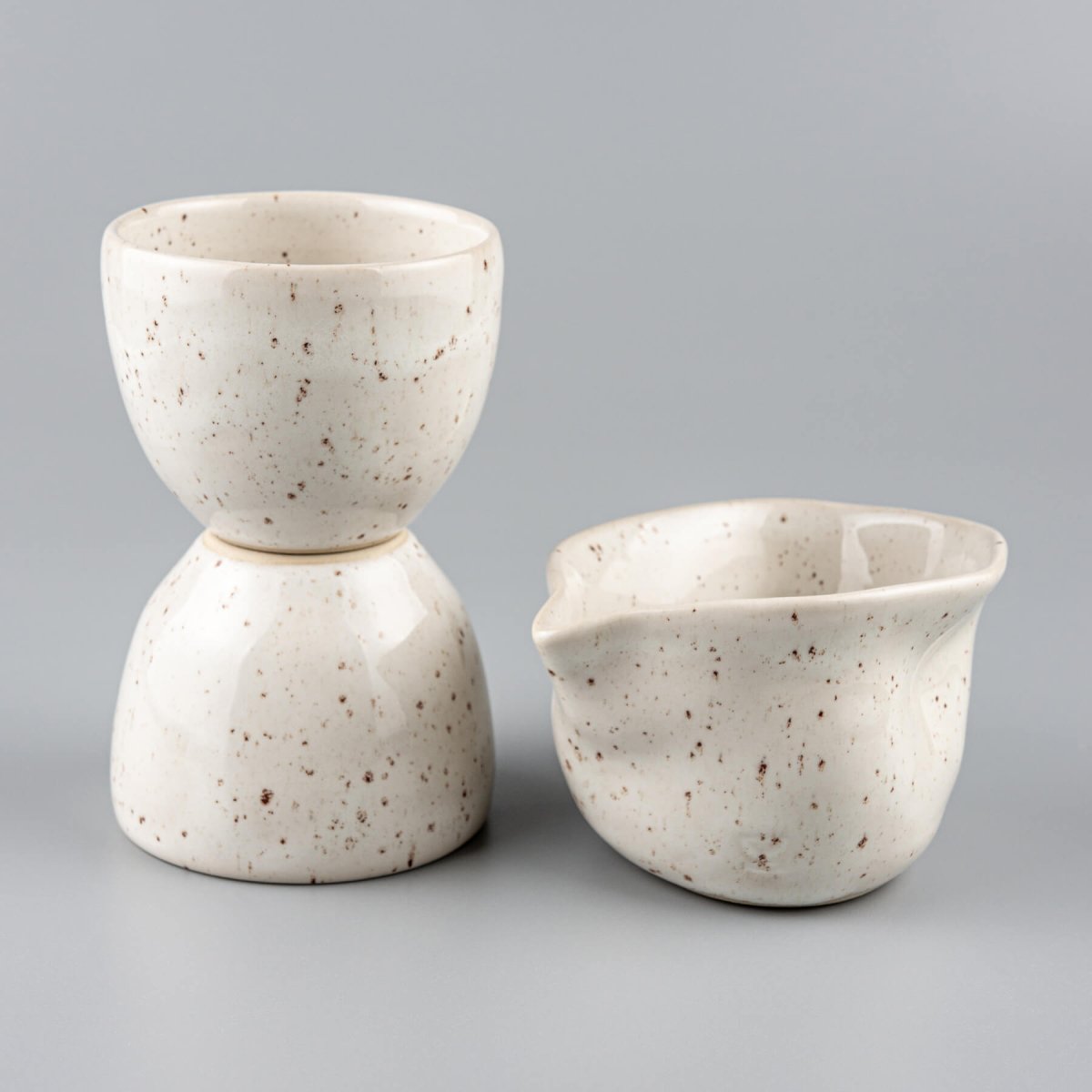 Minimalist stoneware coffee cups in ivory glaze with speckled design for interior design and culinary presentation.