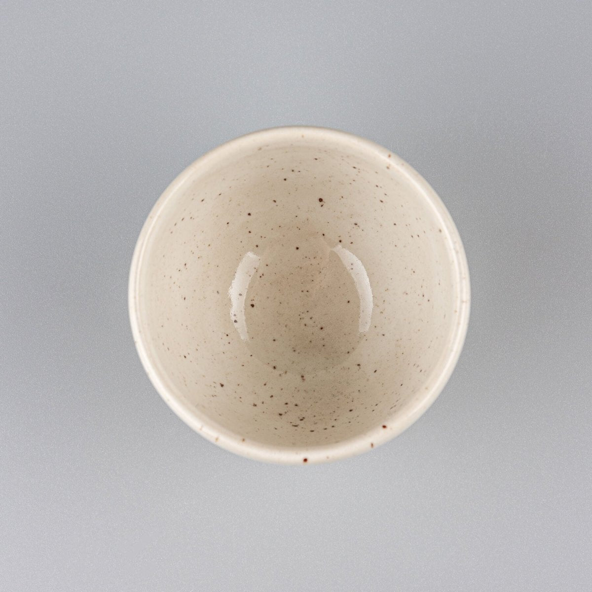 Top view of a handcrafted coffee cup with glossy ivory glaze, perfect for culinary presentation.