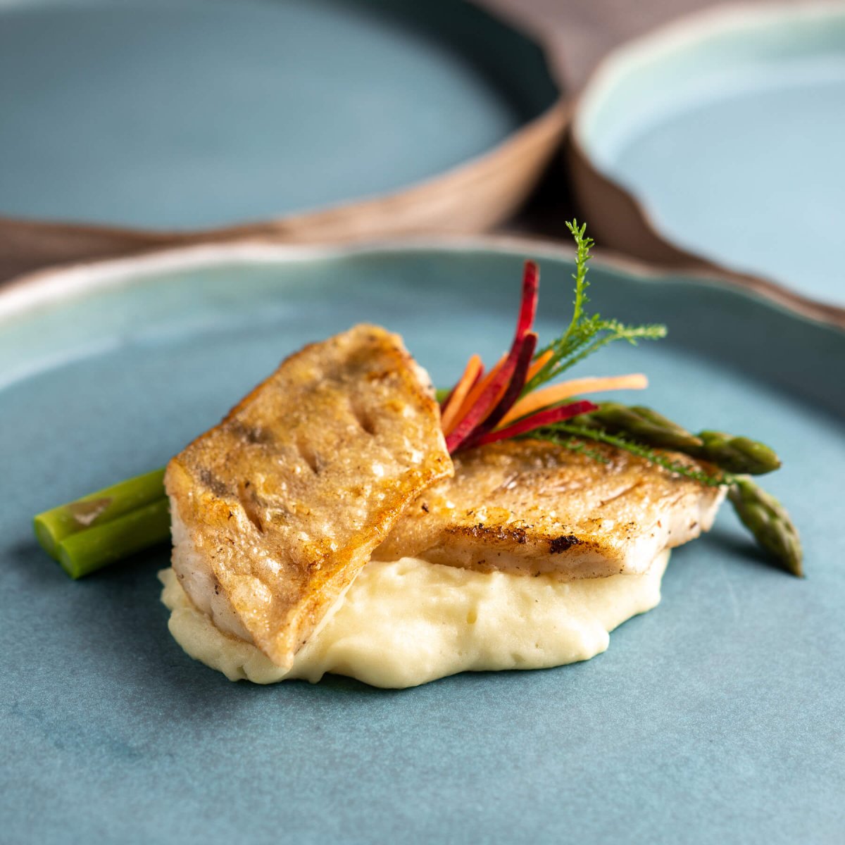 Handmade turquoise dinner plate elegantly presenting gourmet dish for fine dining experience.