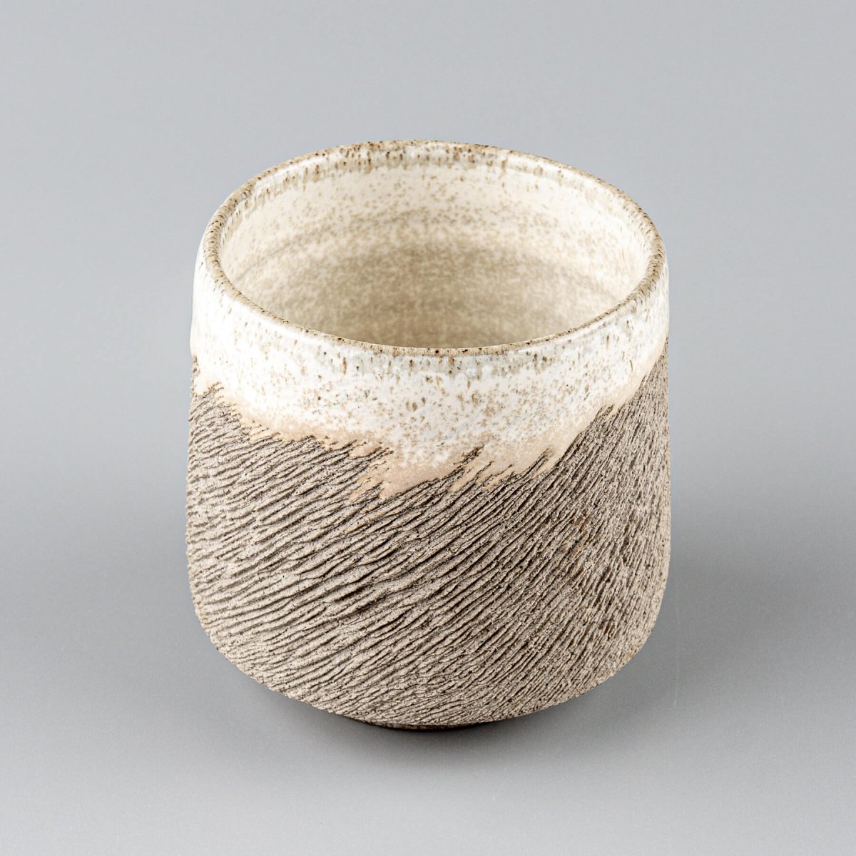 Top view of handmade stoneware coffee cup with white glaze interior, for kitchenware, tableware, and culinary presentation.