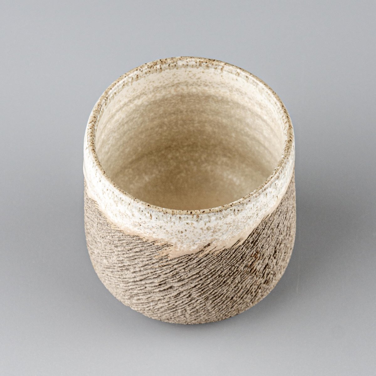 Elegant stoneware coffee cup with carved exterior detail and artistic glaze, suitable for fine dining restaurants and hotels.