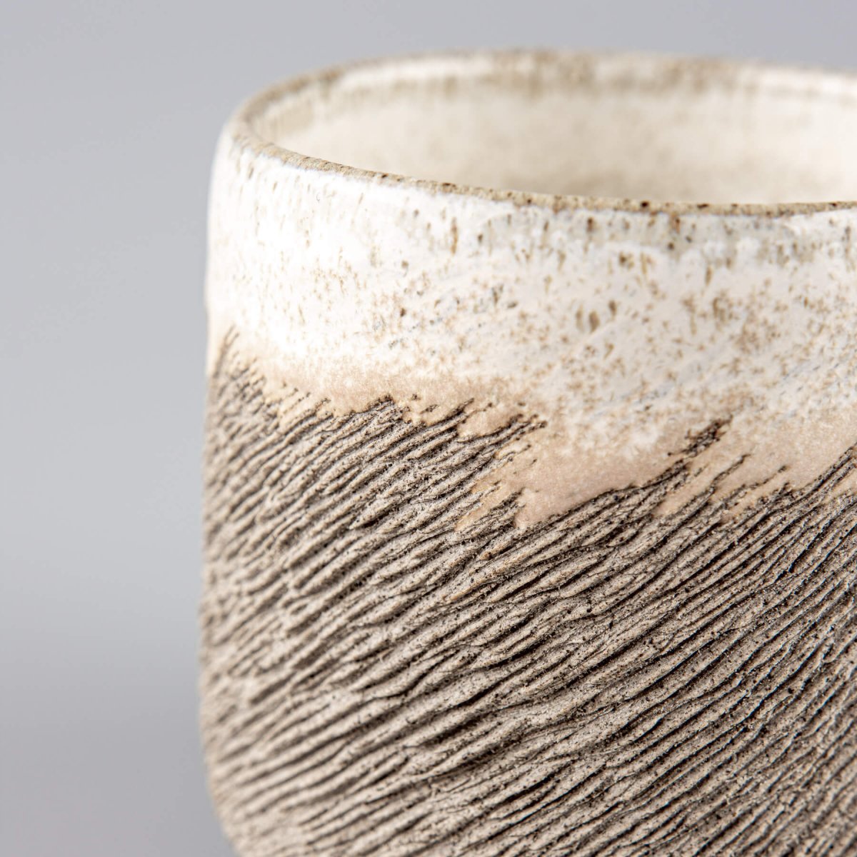 Close-up of textured stoneware coffee cup highlighting natural clay finish and handmade craftsmanship for interior design.