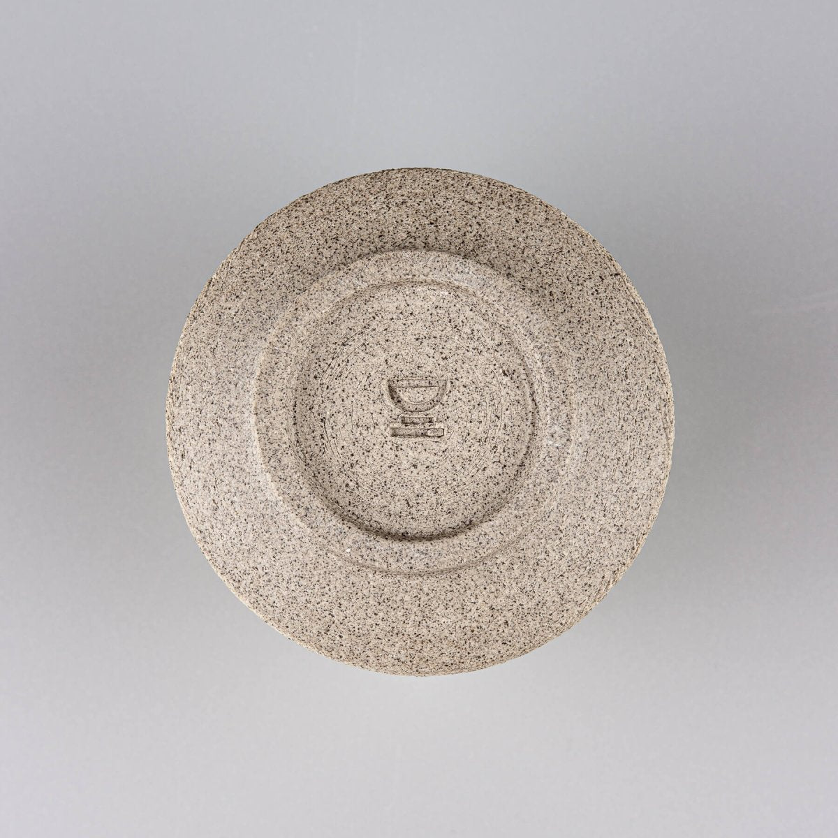 Base of handmade stoneware coffee cup with carved foot and natural clay finish, reflecting artisanal craftsmanship.