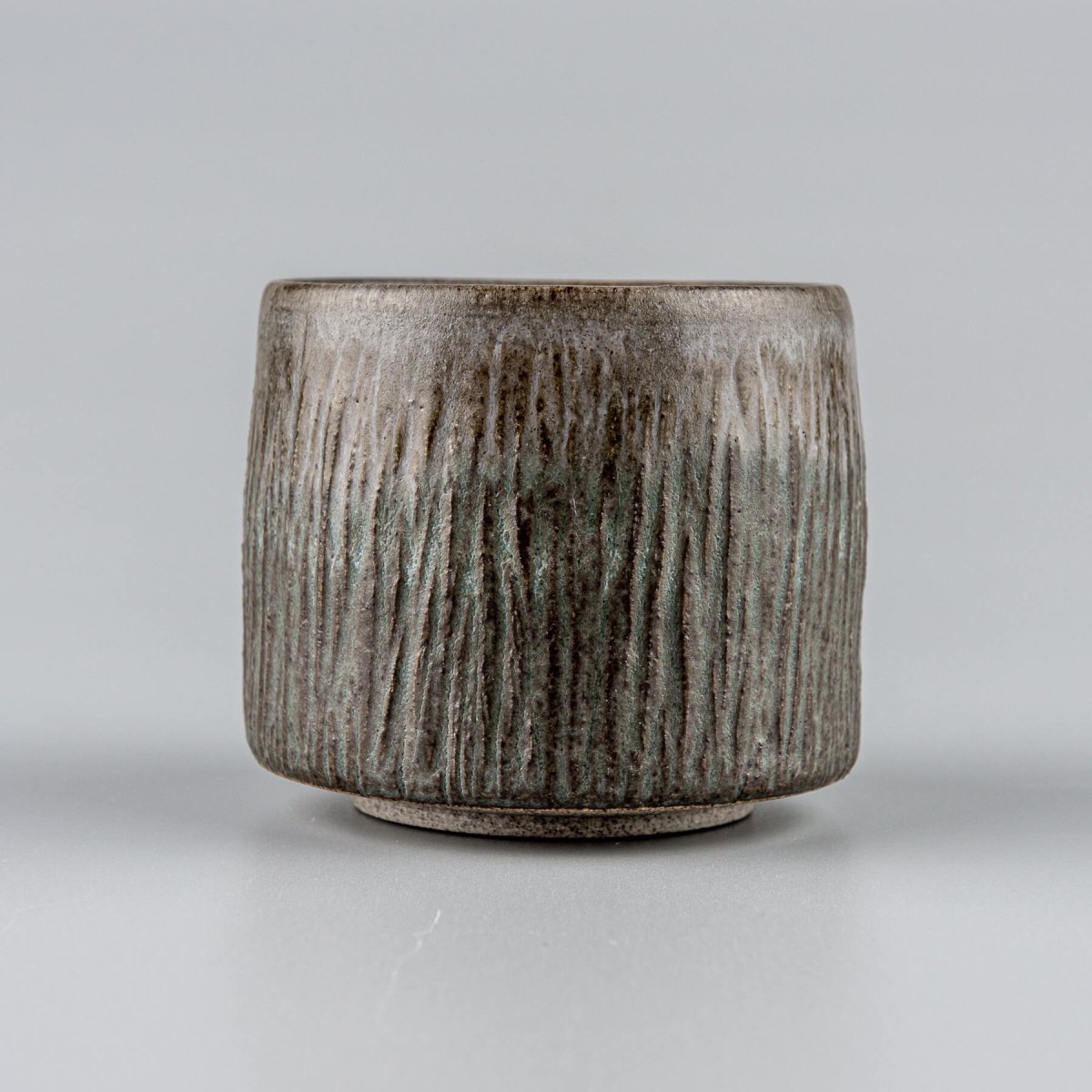 Handcrafted stoneware coffee cups with dark matte glaze and carved texture, perfect for fine dining tableware.