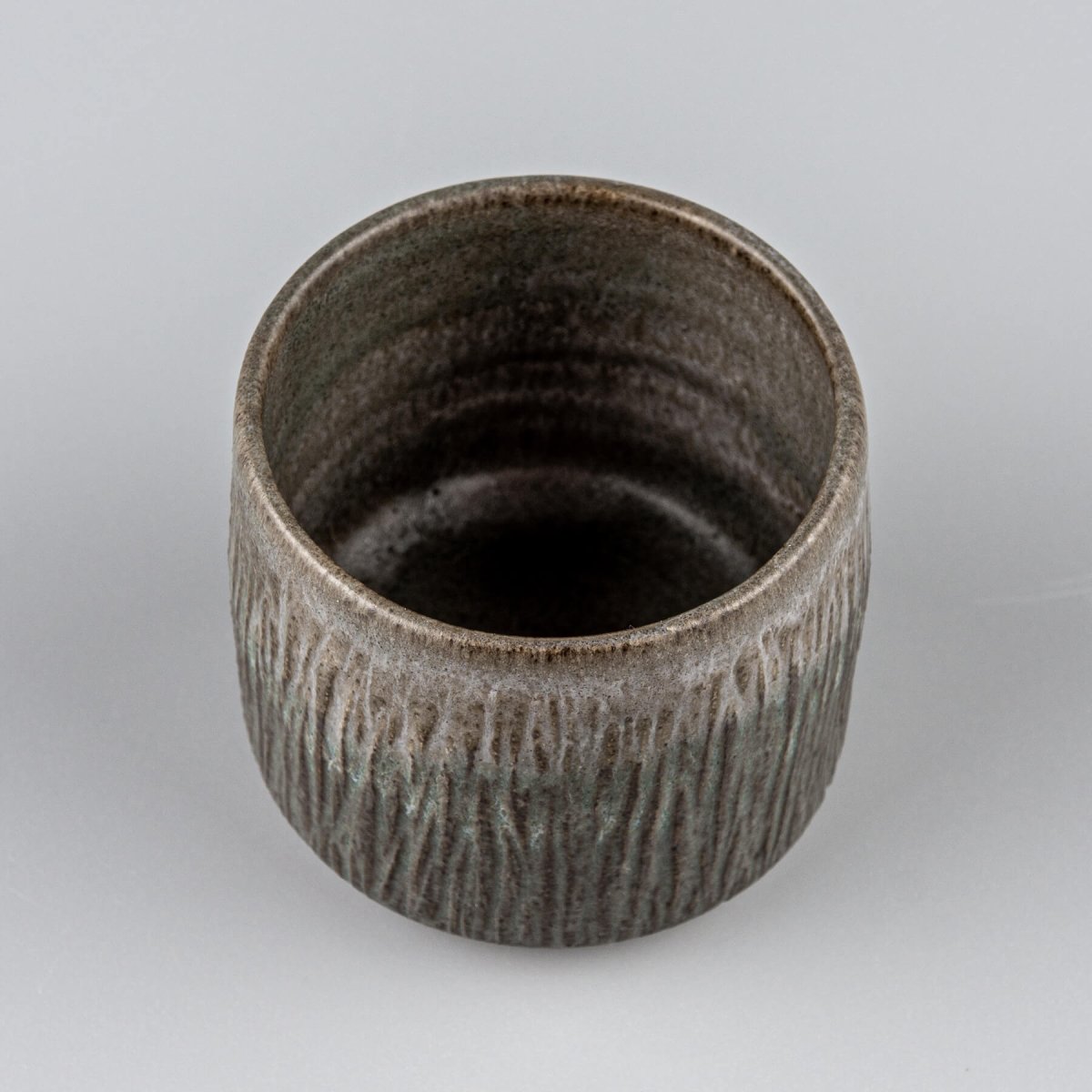 Dark stoneware coffee cups with flat edges and carved exterior, suitable for restaurants and housewarming gifts.