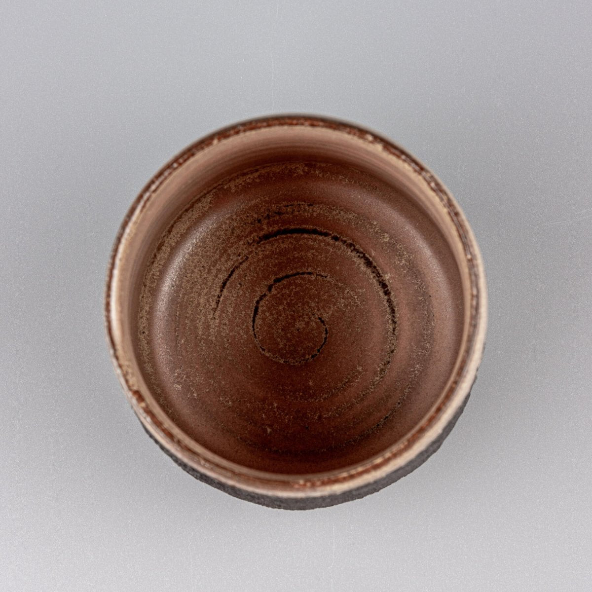 Top view of artisanal pottery mug with smooth glazed interior and textured stoneware exterior for culinary use.