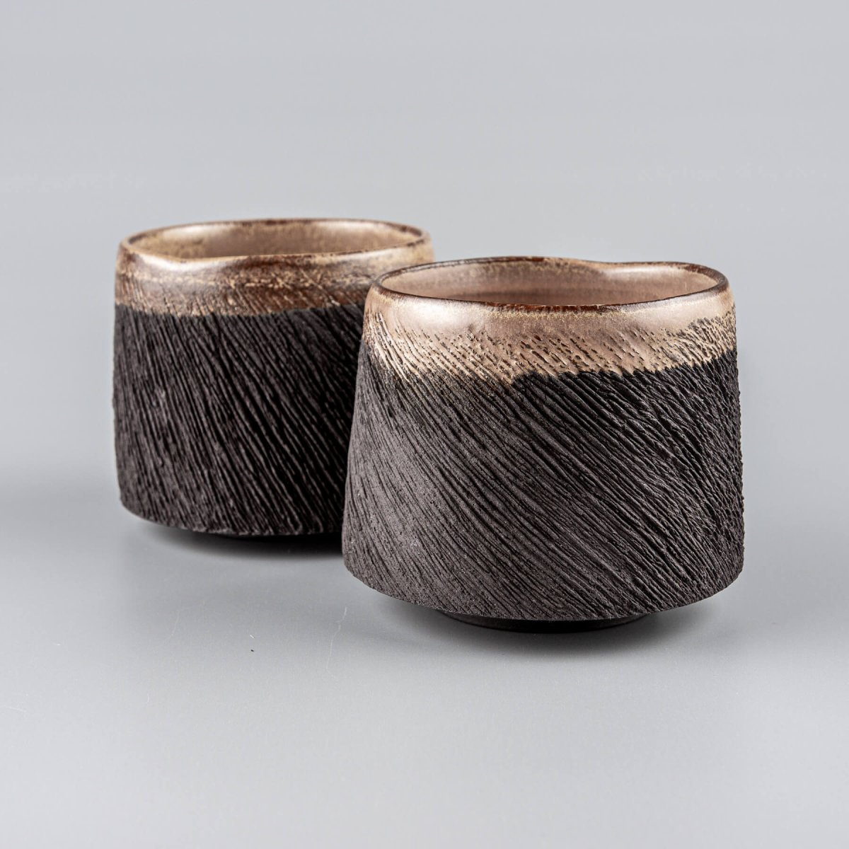Handcrafted pottery mugs with black stoneware clay and carved textured design for fine dining and home decor.