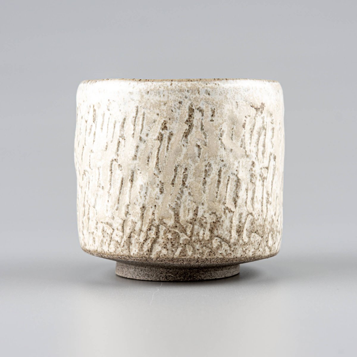 Rustic ceramic espresso cup with carved surface and minimal design for tableware and decor.