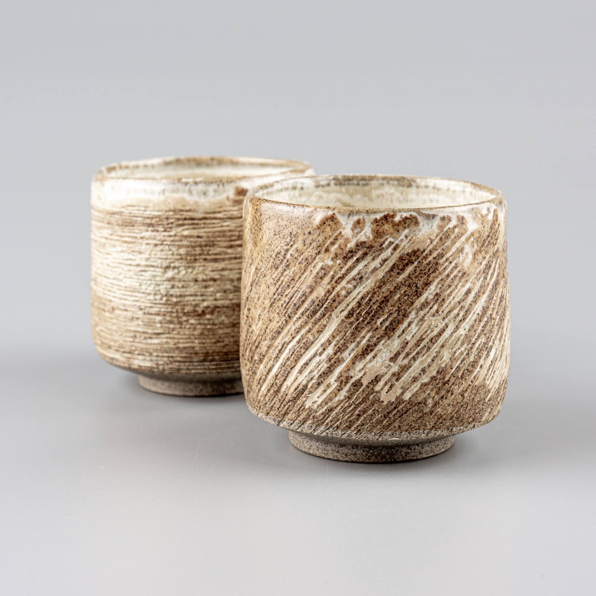 Handmade ceramic mugs with carved diagonal texture and matte glaze for home and restaurant use.