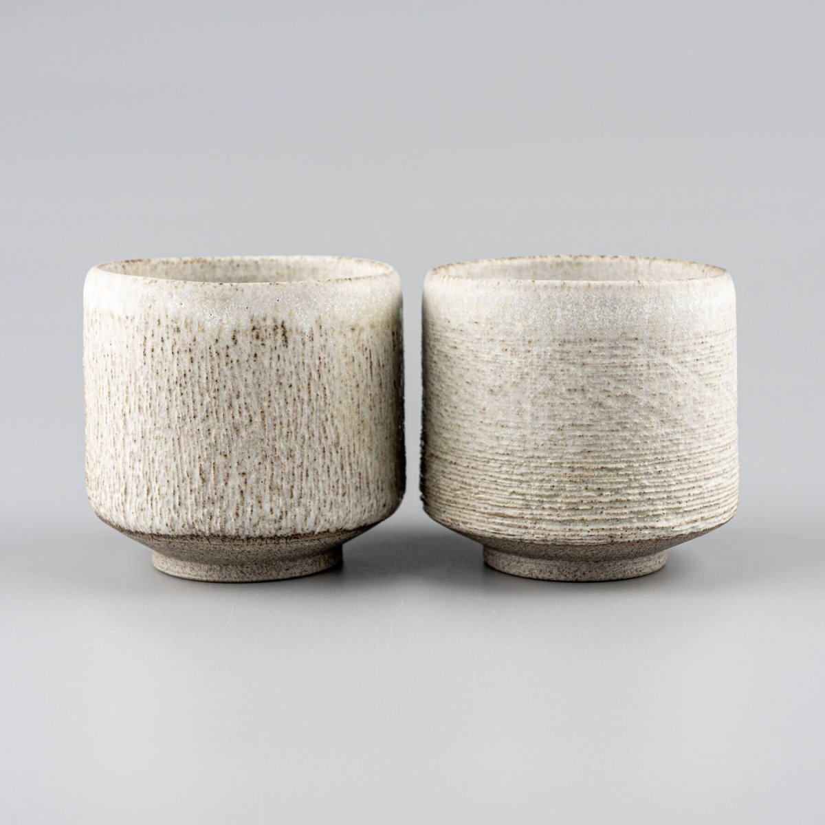 Elegant ceramic mugs with textured carving, perfect for fine dining and handmade decor.