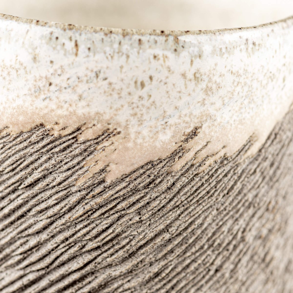 Close-up of rustic stoneware coffee cup showing carved textured surface and semi-gloss white glaze, ideal for fine dining.