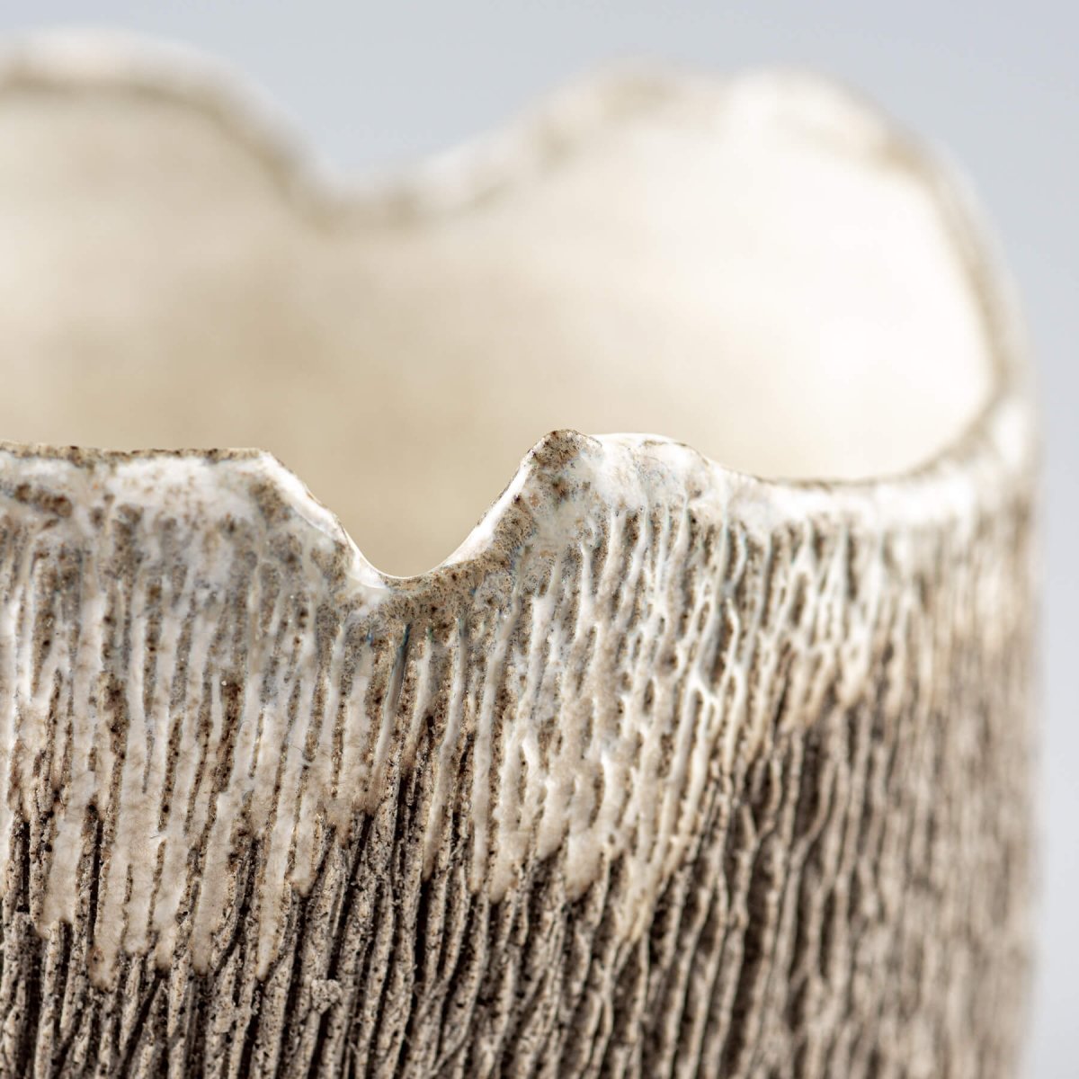 Detail of irregular rim stoneware coffee cup highlighting artisan craftsmanship.