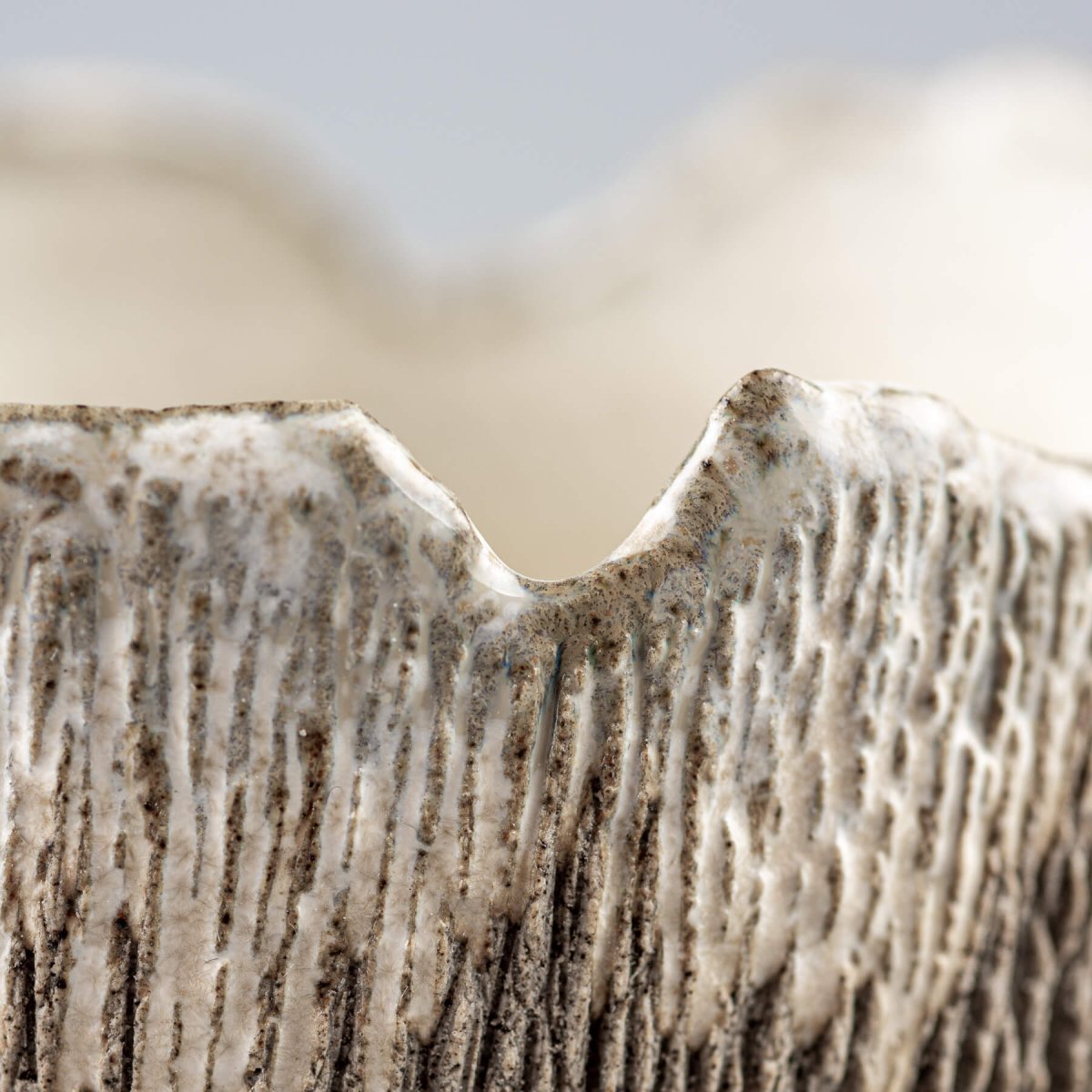 Close-up of carved vertical texture on handmade stoneware coffee cup for home and restaurants.