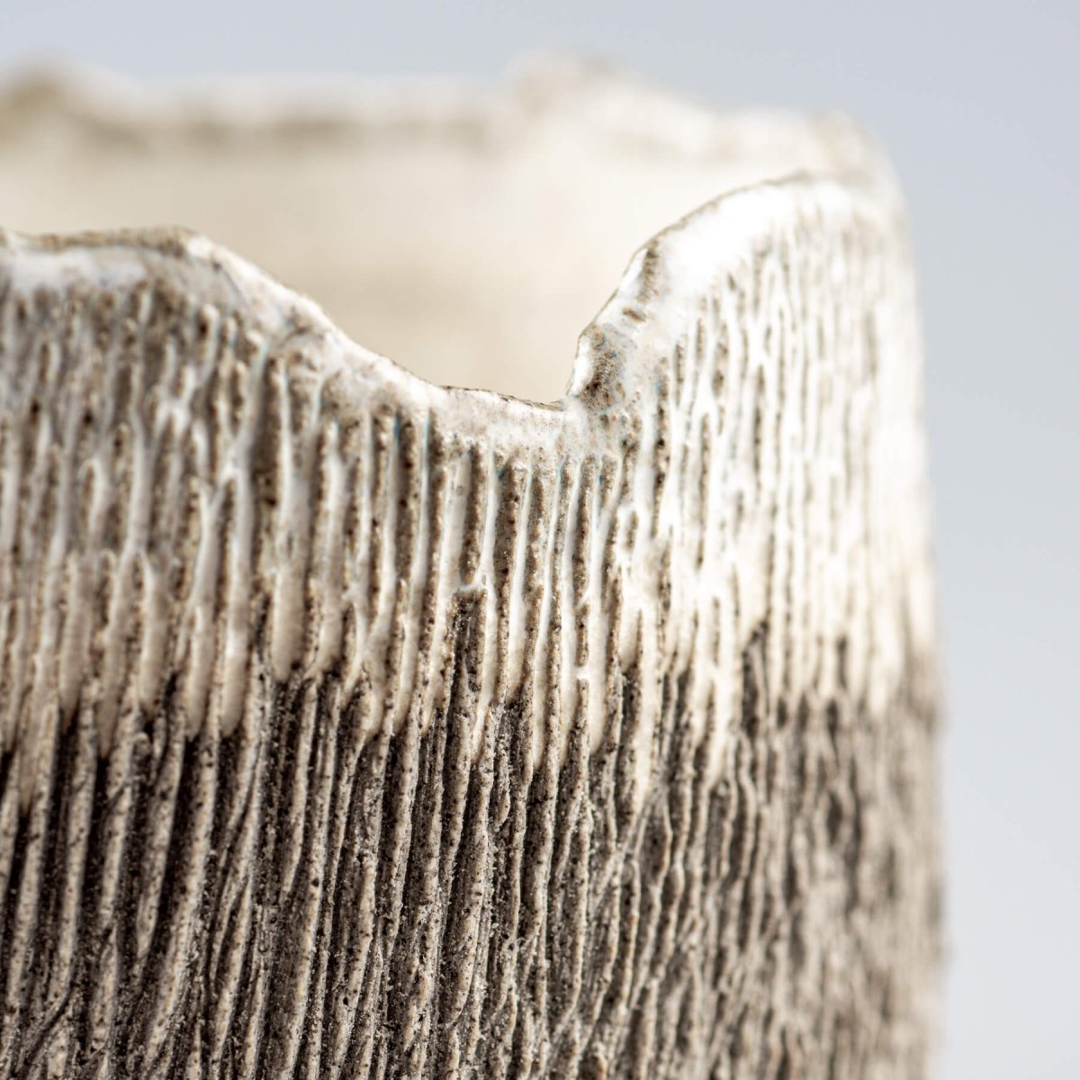 Detail view of irregular rim on artisanal stoneware coffee cup, ideal for boutique hotels.