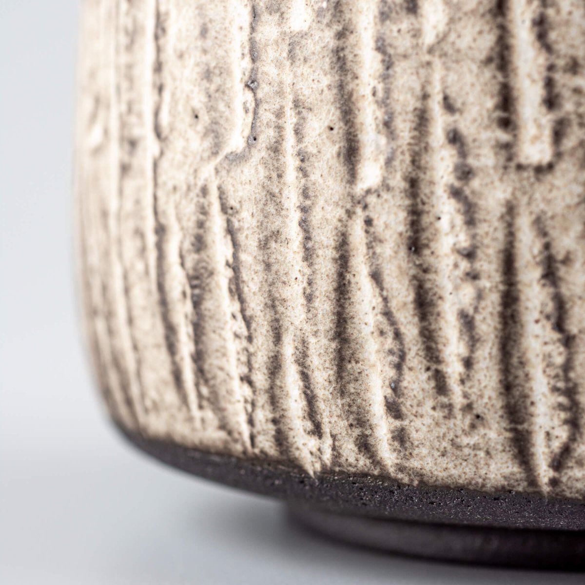 Side close-up of a handcrafted ceramic mug highlighting unique pottery texture and glaze finish.