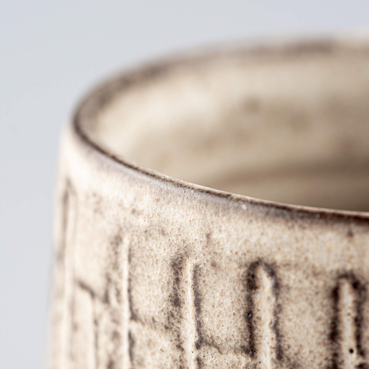 Close detail of a handcrafted ceramic mug rim with stoneware texture and modern design.