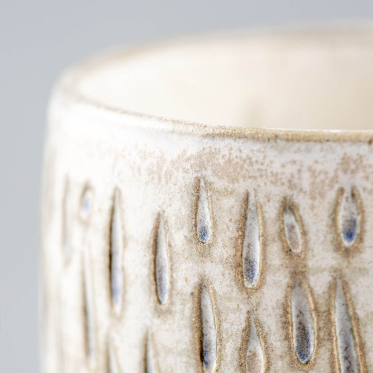 Detailed side view of handmade ceramic espresso cup with elegant droplet carving.