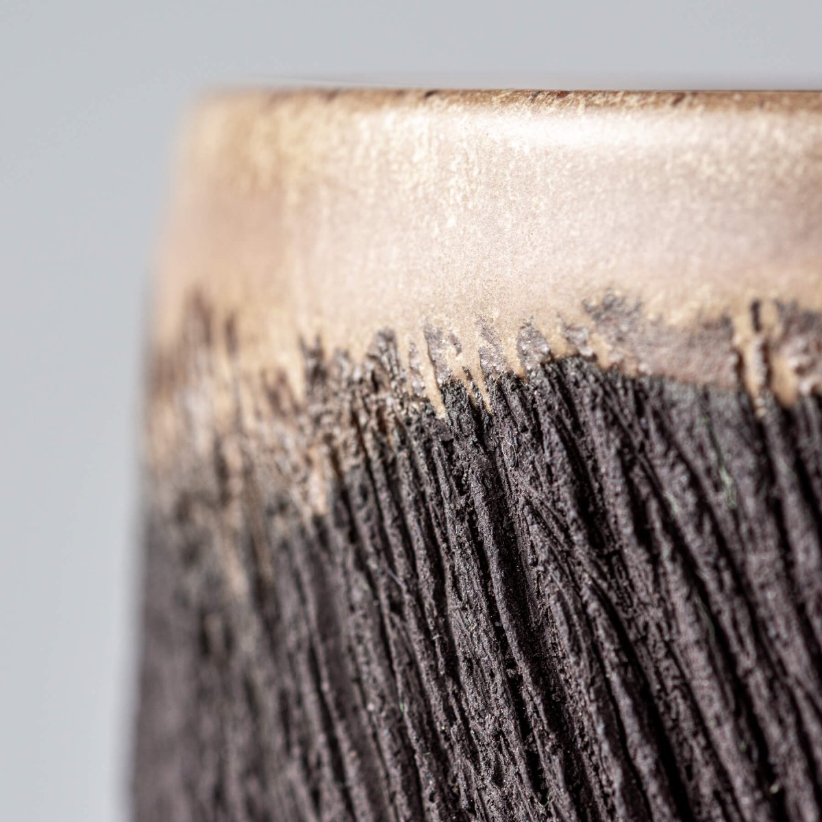 Close-up of textured black pottery mug surface highlighting artisanal craftsmanship for handmade decor and tableware.