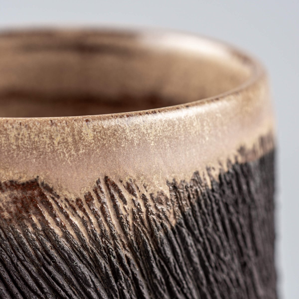 Semi-gloss glazed rim of handcrafted pottery mug, blending rustic design with modern interior decor appeal.