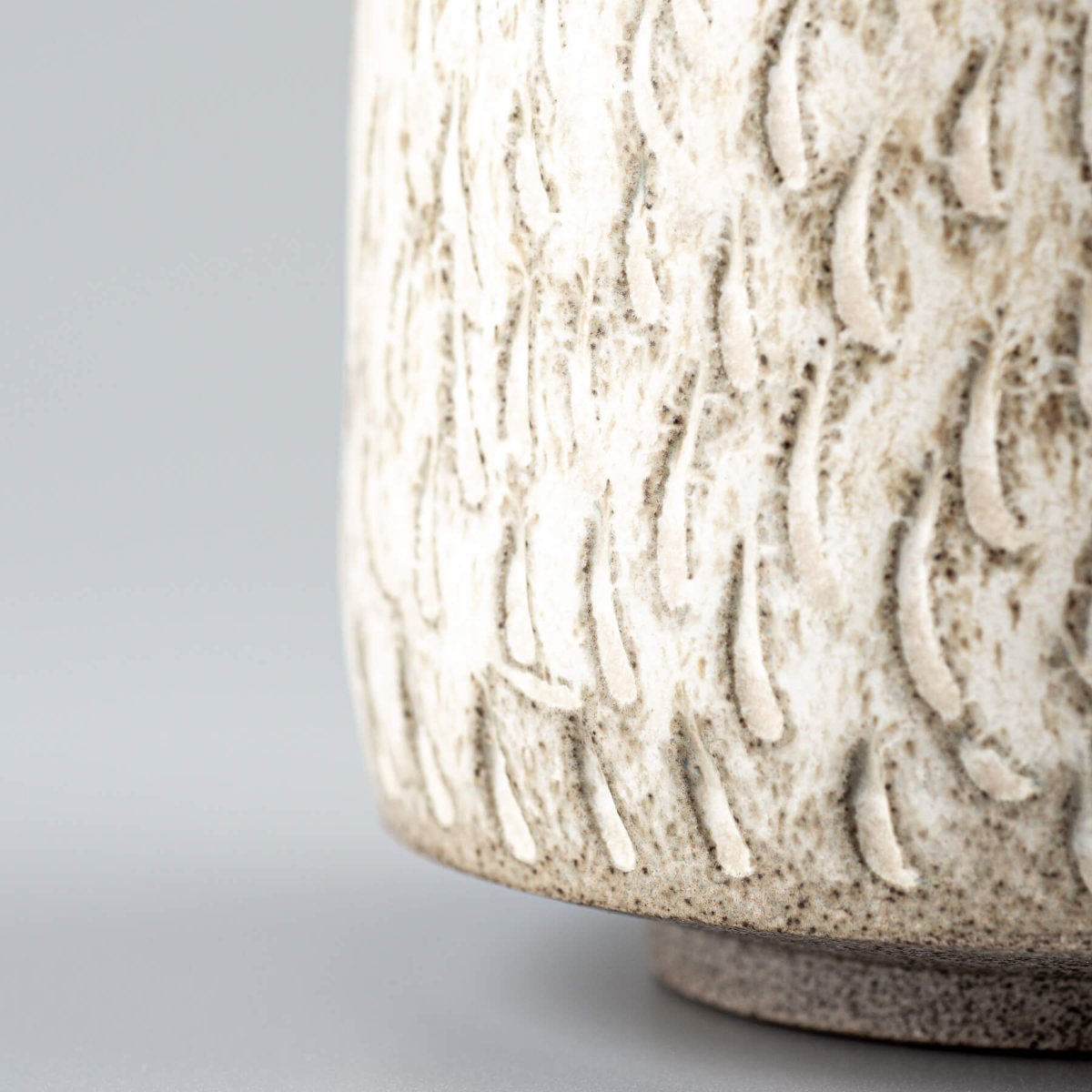 Close-up of textured ceramic espresso cup surface with artisan hand-carved design.
