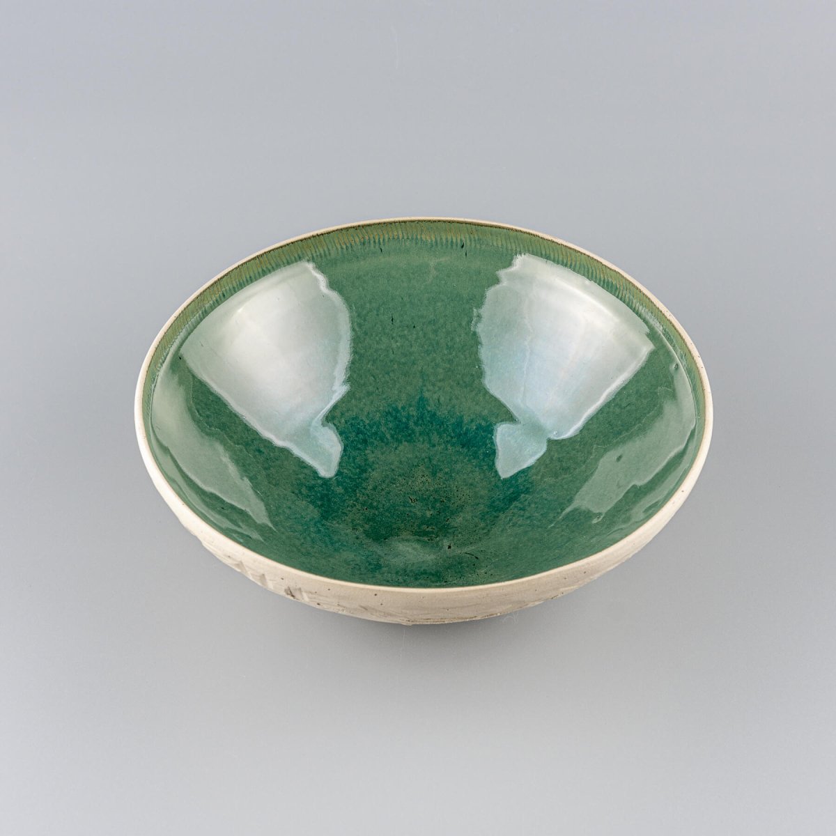 Close-up of hand-carved white stoneware surface revealing detailed texture of ceramic bowl.