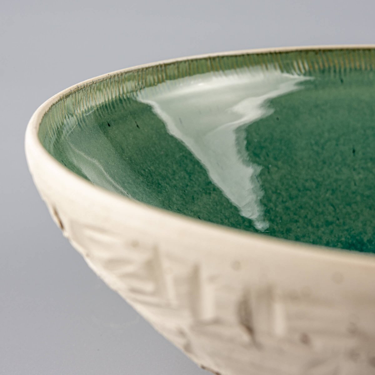 Detail of side carving pattern on ceramic bowl showing chiseled artisan texture.