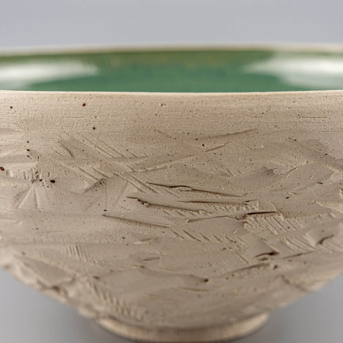 Profile angle of ceramic bowl highlighting raw white clay and contrasting glazed interior.
