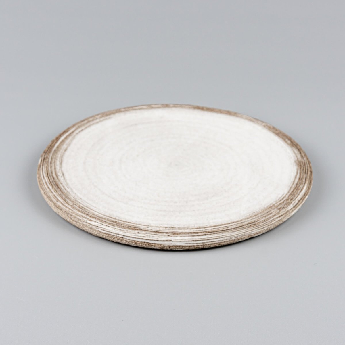 Close-up of carved rim on flat handmade ceramic plate for elegant plating.